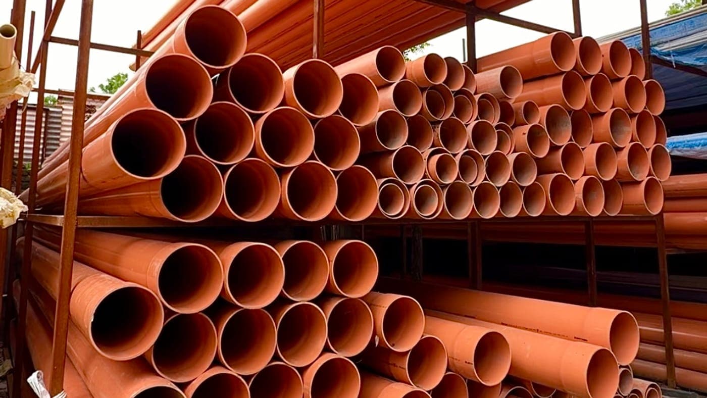 Orange drainage pipes stacked on a rack in the yard