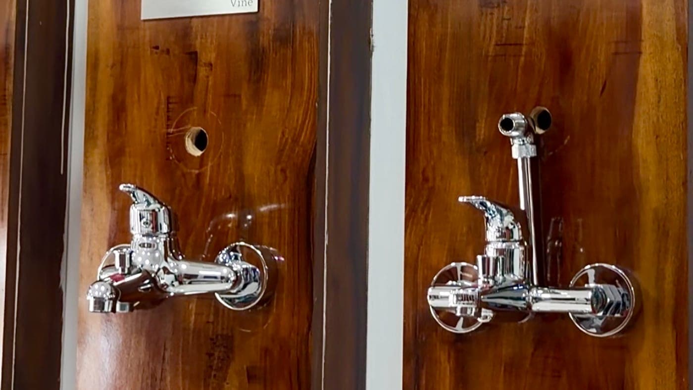 Two chrome wall mixers mounted on wooden display panels in the showroom