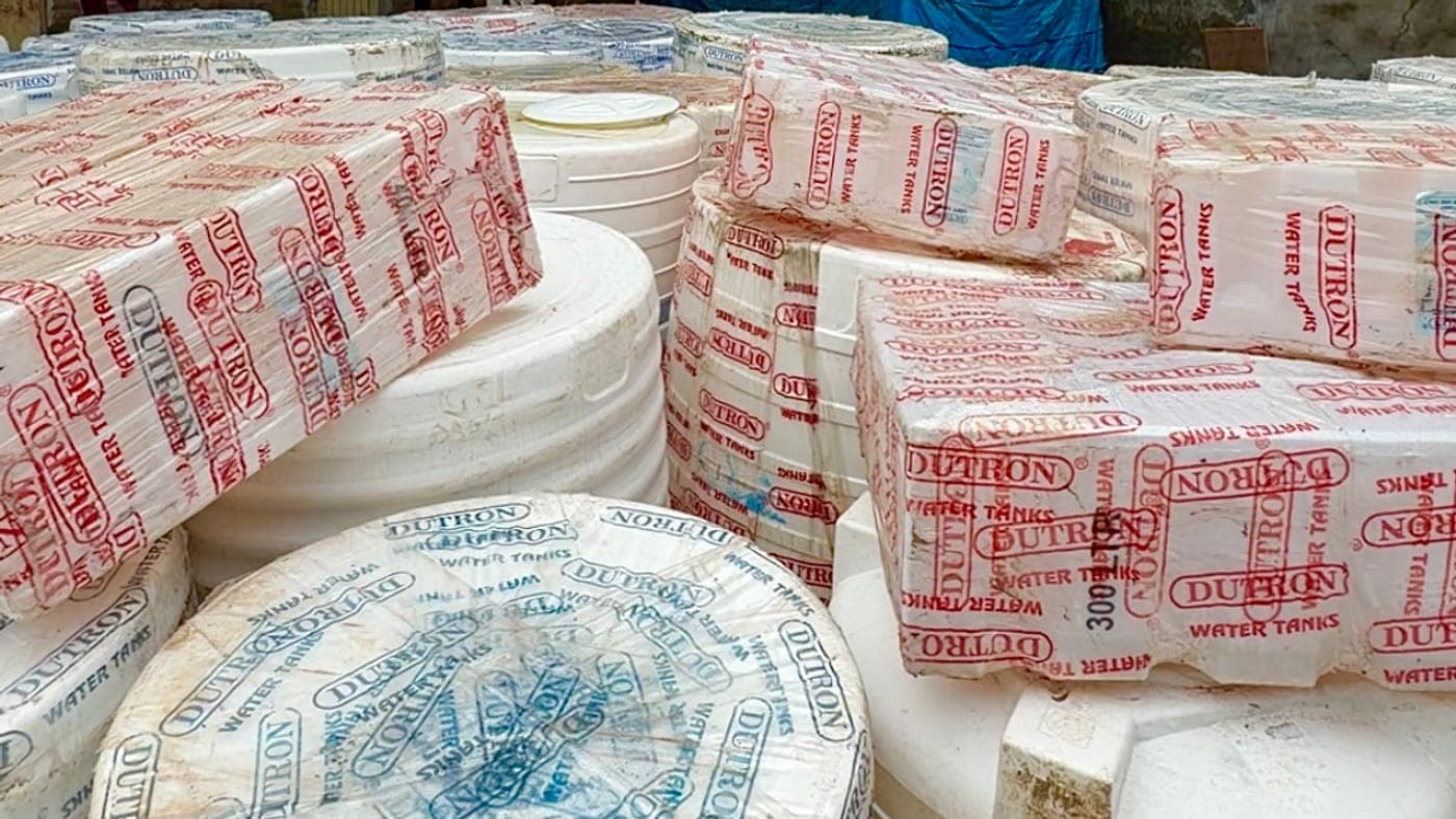 Dutron water tanks in their printed plastic wrapping, stacked at the godown