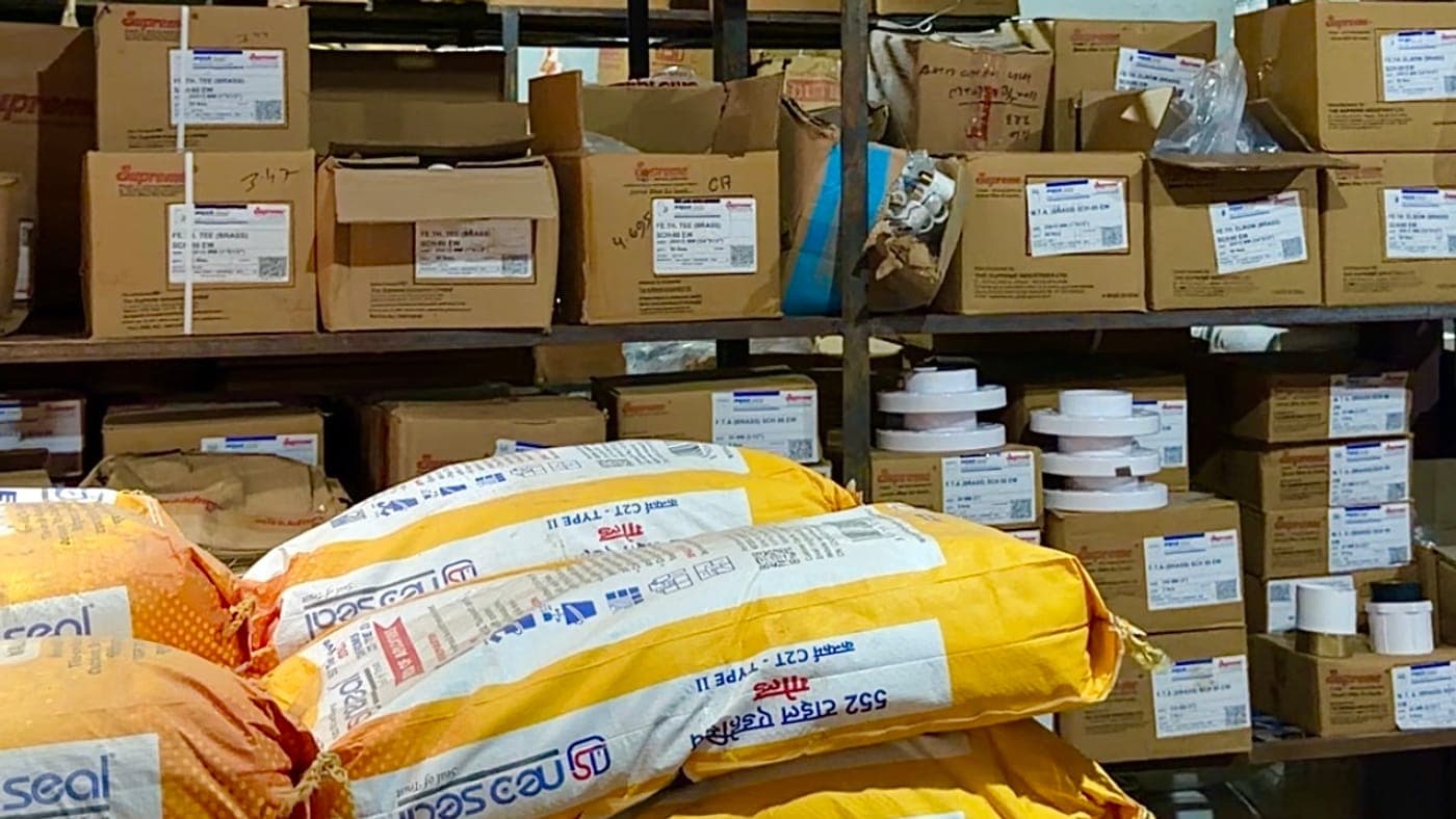 Bags of NeoSeal tile adhesive in front of shelves of boxed Supreme fittings
